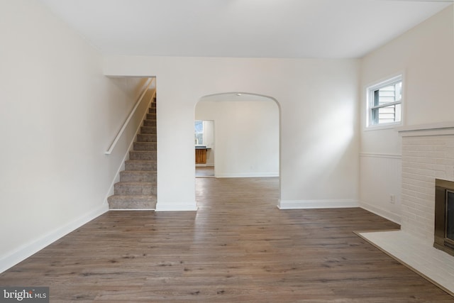 unfurnished living room featuring hardwood / wood-style floors and a brick fireplace