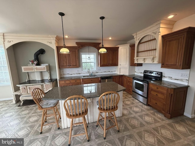 kitchen featuring appliances with stainless steel finishes, backsplash, sink, decorative light fixtures, and a center island