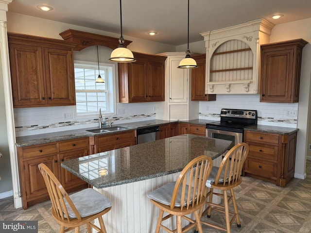 kitchen with appliances with stainless steel finishes, dark stone counters, sink, a kitchen island, and hanging light fixtures