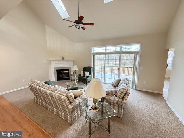 living room featuring a skylight, light colored carpet, ceiling fan, high vaulted ceiling, and a fireplace