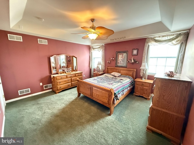 bedroom featuring dark colored carpet, ceiling fan, and a tray ceiling