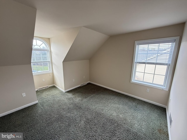 bonus room featuring dark colored carpet, a wealth of natural light, and lofted ceiling