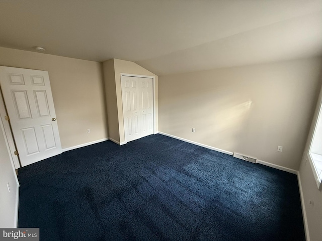 unfurnished bedroom with carpet flooring, vaulted ceiling, and a closet