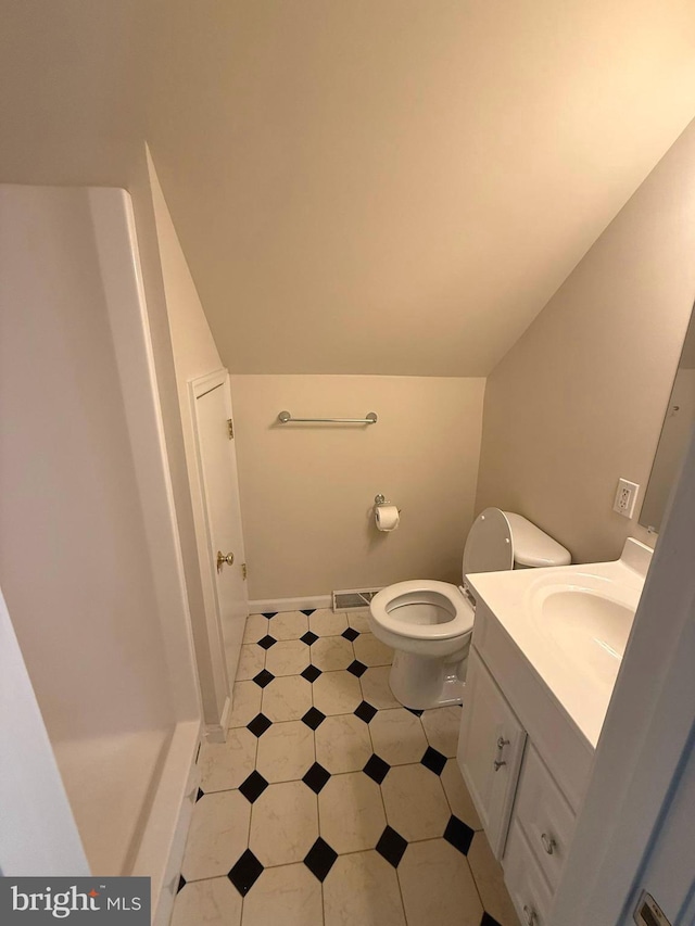 bathroom with tile patterned floors, vanity, vaulted ceiling, and toilet