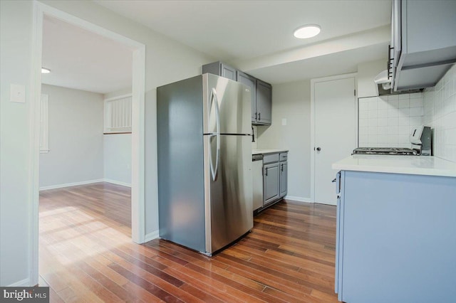 kitchen with gray cabinets, stainless steel fridge, decorative backsplash, and range