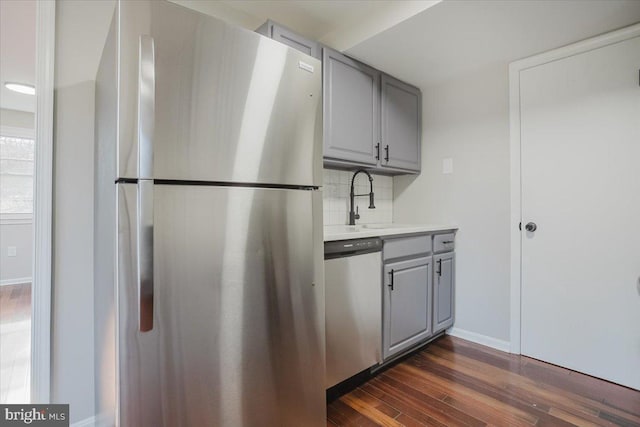 kitchen featuring appliances with stainless steel finishes, gray cabinets, tasteful backsplash, and dark wood-type flooring