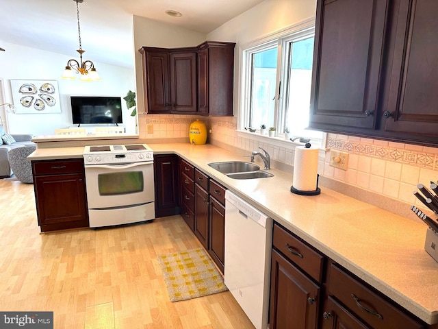 kitchen with sink, white appliances, light hardwood / wood-style flooring, hanging light fixtures, and vaulted ceiling