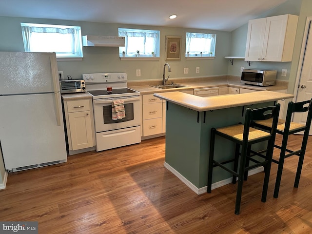 kitchen with sink, white appliances, light hardwood / wood-style flooring, a kitchen breakfast bar, and white cabinets