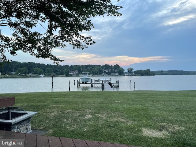 view of dock with a water view and a lawn