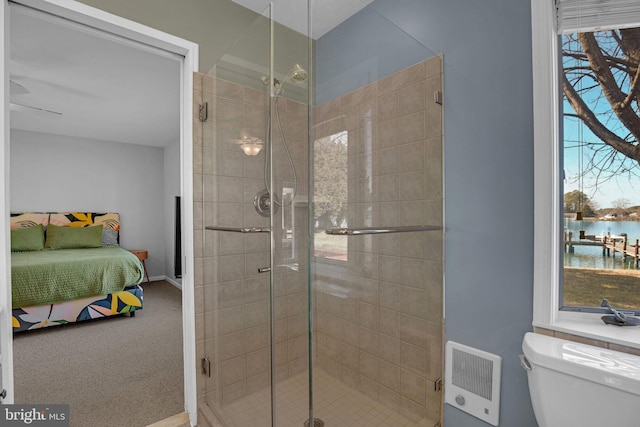 bathroom featuring a shower with door, a water view, heating unit, and toilet