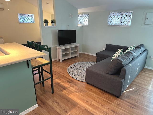 living room with wood-type flooring, lofted ceiling, electric panel, and a wall unit AC