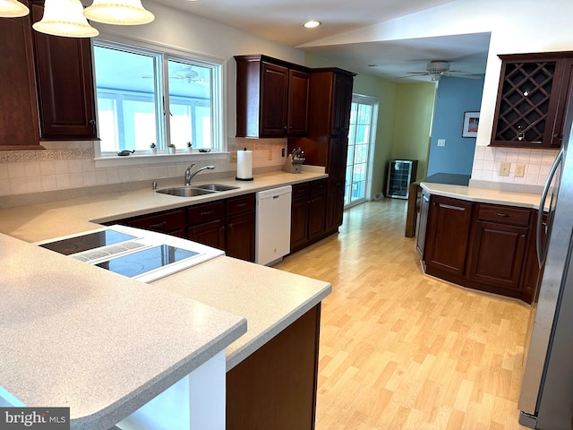 kitchen featuring sink, light hardwood / wood-style flooring, white dishwasher, decorative light fixtures, and kitchen peninsula