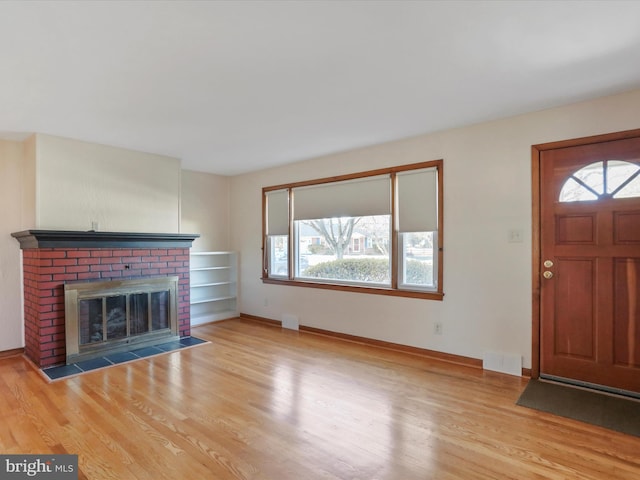 unfurnished living room featuring a fireplace and light hardwood / wood-style floors