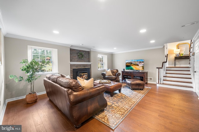 living room with a stone fireplace, a wealth of natural light, and crown molding