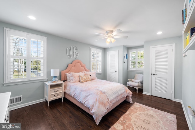 bedroom featuring two closets, ceiling fan, and dark hardwood / wood-style floors