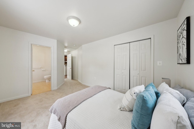 bedroom with connected bathroom, light carpet, and a closet