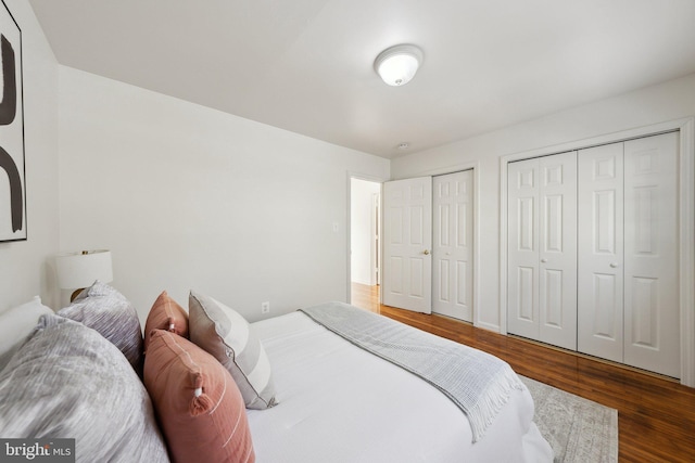 bedroom featuring dark wood-type flooring and multiple closets