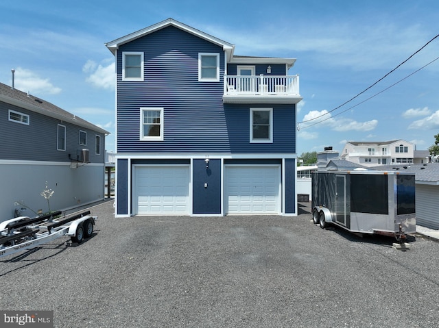 rear view of property featuring a balcony and a garage