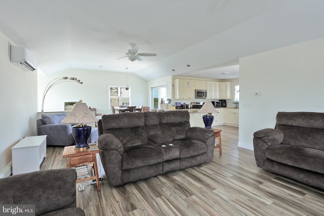 living room with a wall mounted air conditioner, light hardwood / wood-style floors, vaulted ceiling, and ceiling fan