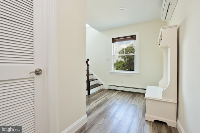 interior space featuring baseboard heating, an AC wall unit, and hardwood / wood-style flooring