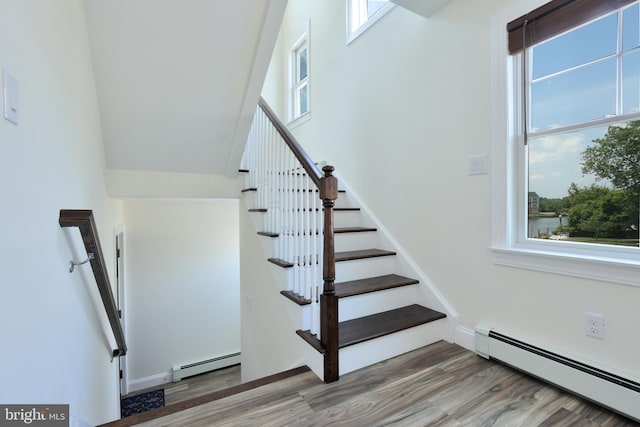 stairway featuring a wealth of natural light and a baseboard heating unit