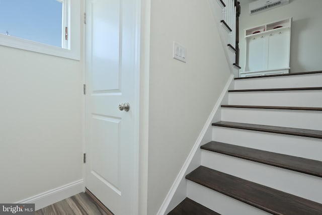 stairway featuring a wall mounted AC and wood-type flooring