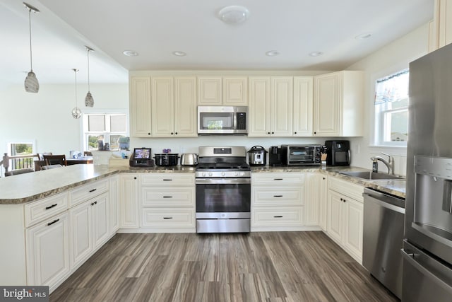 kitchen featuring kitchen peninsula, appliances with stainless steel finishes, dark hardwood / wood-style flooring, sink, and pendant lighting