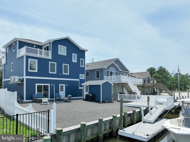 back of property featuring an outdoor living space, a water view, and a shed