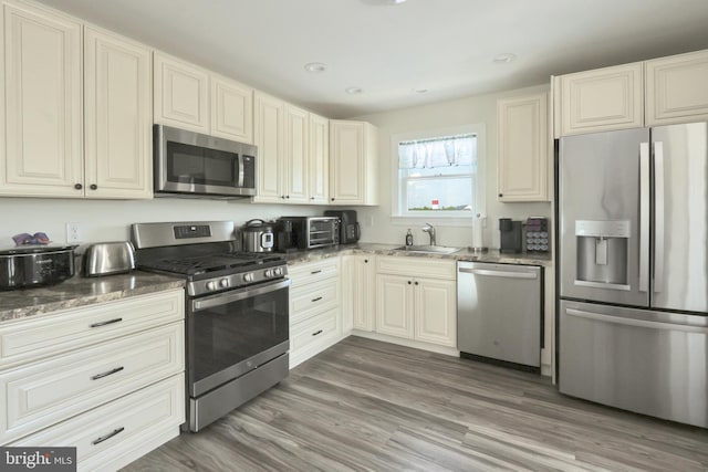 kitchen featuring dark stone countertops, sink, dark hardwood / wood-style flooring, and appliances with stainless steel finishes