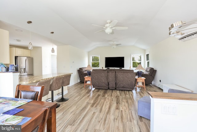 living room featuring ceiling fan, vaulted ceiling, and light wood-type flooring