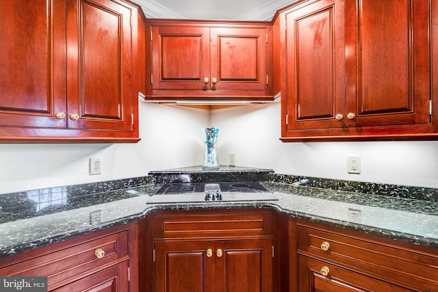 kitchen featuring cooktop and dark stone countertops