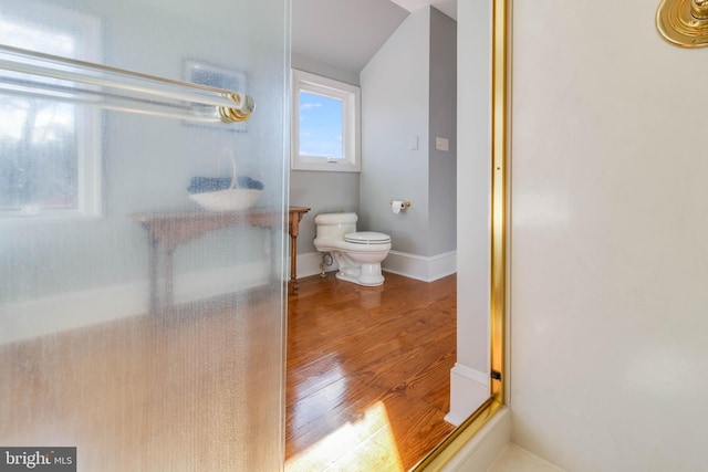 bathroom featuring hardwood / wood-style floors, toilet, and a shower with shower door