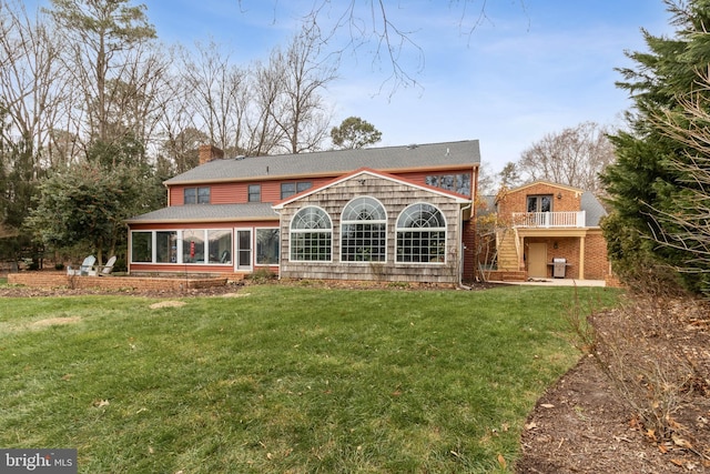 rear view of house with a lawn, a sunroom, and a balcony