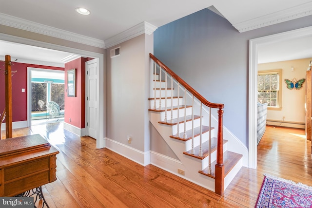 stairs featuring crown molding, wood-type flooring, and a baseboard heating unit