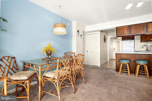 carpeted dining room featuring a textured ceiling and sink