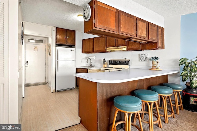 kitchen featuring range with electric cooktop, kitchen peninsula, white refrigerator, and a textured ceiling