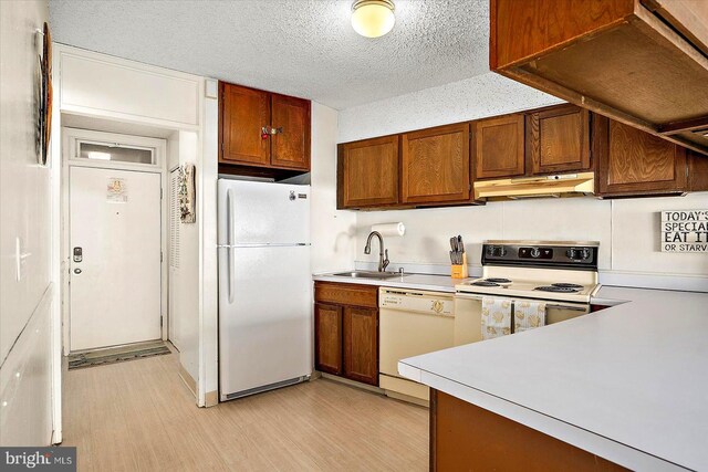 kitchen featuring white appliances, light wood-type flooring, a textured ceiling, and sink