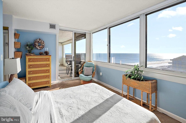 bedroom with a textured ceiling and a water view