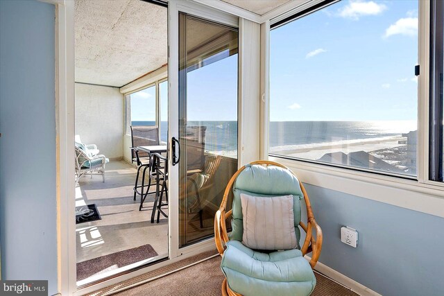 living area with a textured ceiling, carpet, and a water view