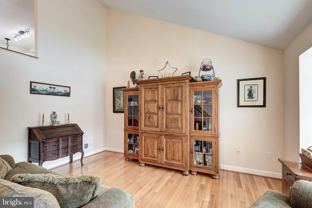 sitting room featuring visible vents, baseboards, light wood-style floors, and lofted ceiling