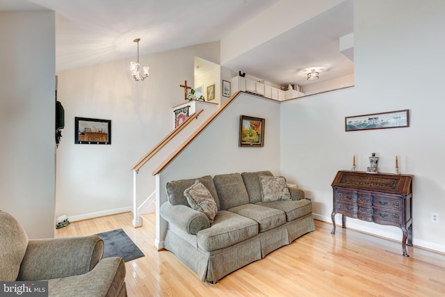 living area featuring lofted ceiling, wood finished floors, stairway, an inviting chandelier, and baseboards