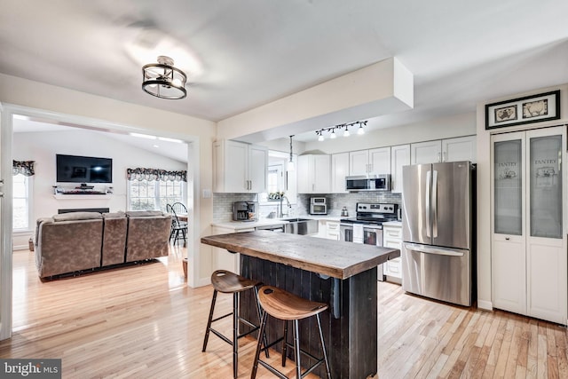 kitchen featuring light wood finished floors, decorative backsplash, white cabinets, and appliances with stainless steel finishes