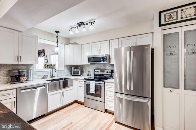 kitchen featuring a sink, decorative backsplash, white cabinetry, and stainless steel appliances