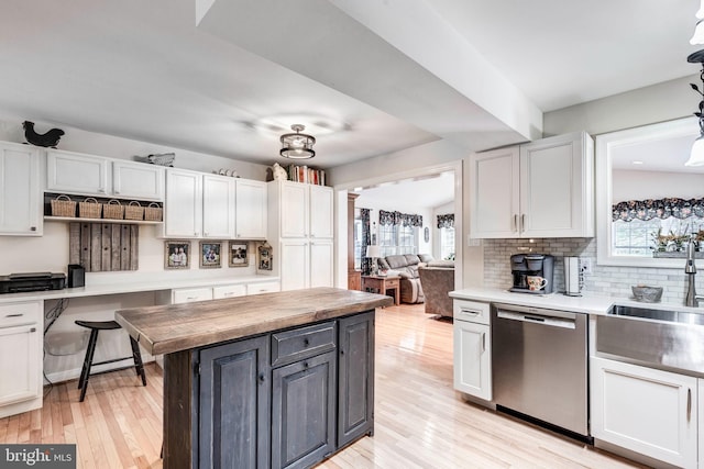 kitchen with backsplash, white cabinetry, light wood-type flooring, and stainless steel dishwasher