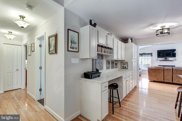 kitchen featuring a kitchen bar, baseboards, light wood-style floors, and light countertops