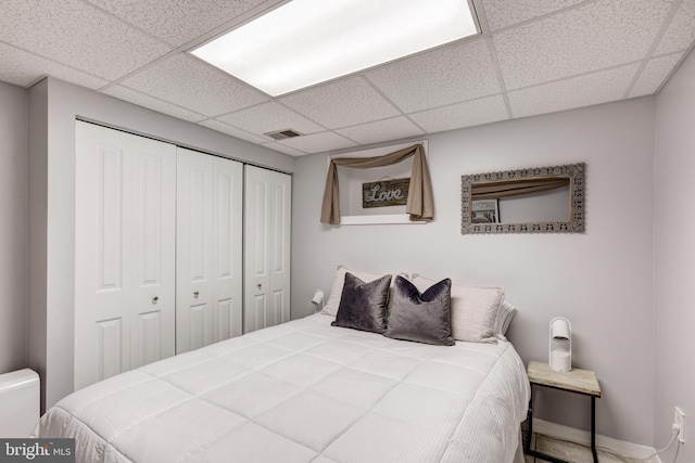 bedroom with visible vents, a closet, and a drop ceiling