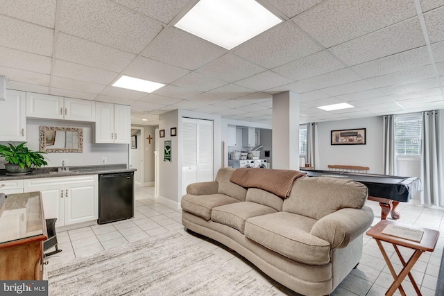 living area featuring wet bar, light tile patterned floors, and a paneled ceiling