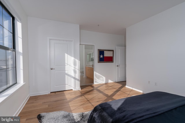 bedroom with connected bathroom and light hardwood / wood-style flooring