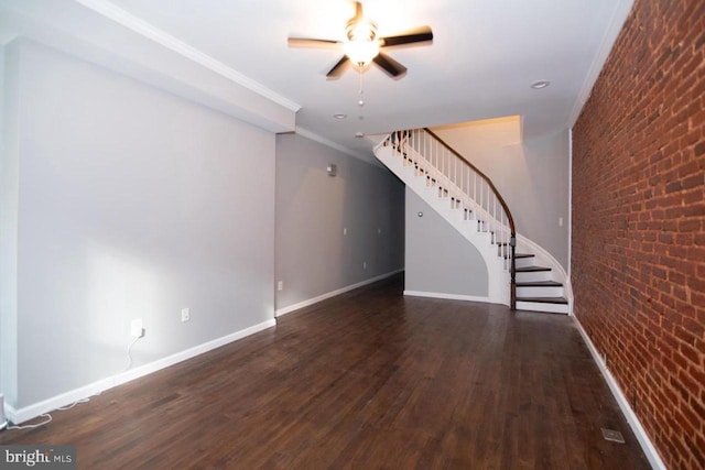 unfurnished living room featuring dark hardwood / wood-style flooring, ceiling fan, ornamental molding, and brick wall