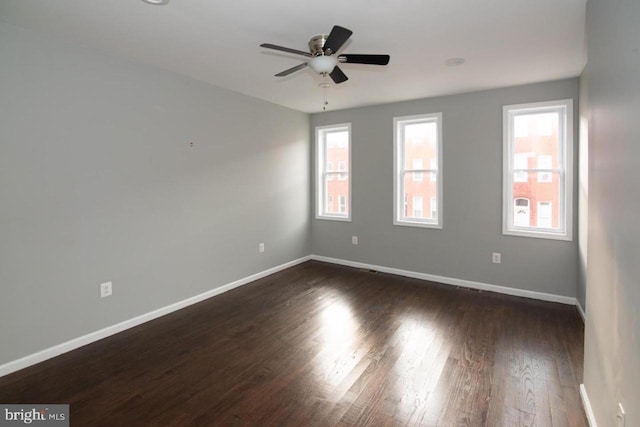 unfurnished room with ceiling fan, plenty of natural light, and dark wood-type flooring